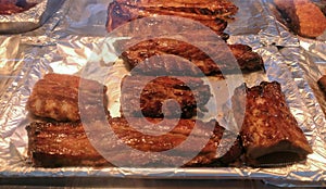 Roasted marinated pork ribs for sale on display in thermal counter in deli department of supermarket