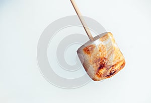 Roasted marshmallows on a skewer on white background