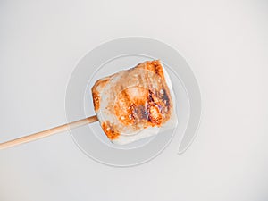 Roasted marshmallows on a skewer on white background