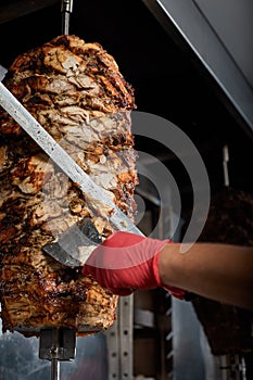 Roasted meat on the bone for the preparation of donors or shawarma. Close-up. The cook cuts the meat fried over charcoal