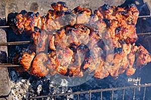 Roasted meat cooked at barbecue, closeup. Spicy marinated meat cook on bbq grill. Pork meat, shashlik, prepared on grill