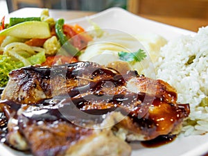 Roasted meat served with mashed potato, rice, and vegetable salad