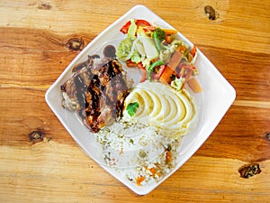 Roasted meat served with mashed potato, rice, and vegetable salad