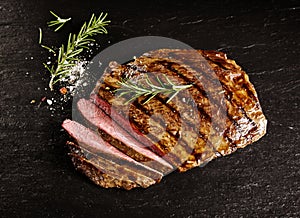 Roasted medium rare sliced flank beef with rosemary photo