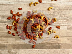 Roasted Natural Almond Nuts Badam and Cashew in an wooden bowl. Nuts spilled on bleached oak wood background. photo
