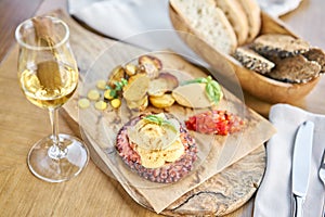 Roasted octopus BBQ and Baked potato with a glass of Grapa. Wooden plate. Restaurant menu photo