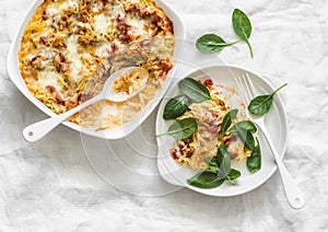 Roasted orzo pasta with tomato sauce and mozzarella cheese served with spinach on a light background, top view