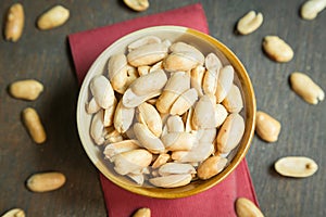 Roasted peeled salted peanuts in rustic bowl on wooden background