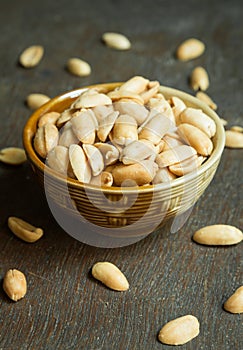 Roasted peeled salted peanuts in rustic bowl on wooden background