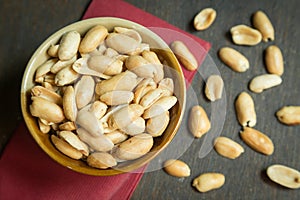 Roasted peeled salted peanuts in rustic bowl on wooden background