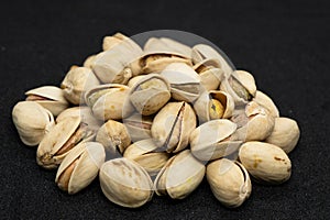 Roasted pistachio nuts in shell on black background, poured roasted peanuts (Pistachio)