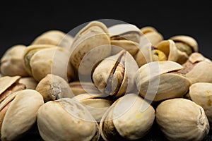 Roasted pistachio nuts in shell on black background, poured roasted peanuts (Pistachio)