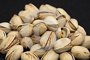 Roasted pistachio nuts in shell on black background, poured roasted peanuts (Pistachio)