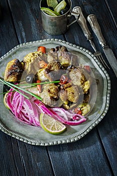 Roasted pork chops with pickled purple onions on retro metal plate on rustic table