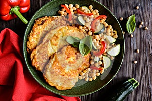 Roasted pork cutlets coated in cheese and breadcrumbs, served with chick peas and vegetable