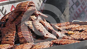 Roasted pork ribs are grilled on charcoal big spinning grill. Street Food Festival. Fried, unhealthy food