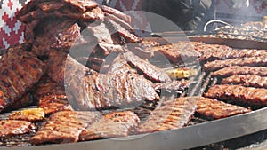 Roasted pork ribs are grilled on charcoal big spinning grill. Street Food Festival. Fried, unhealthy food