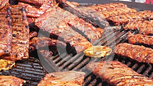 Roasted pork ribs are grilled on charcoal big spinning grill. Street Food Festival. Fried, unhealthy food