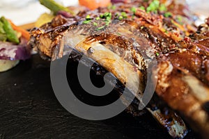 Roasted pork ribs at restaurant against black background with copy space, studio shot, close-up