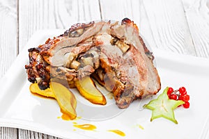 Roasted pork stuffed with mushrooms, peach, carambola, cranberries and sweet sauce on plate on wooden background