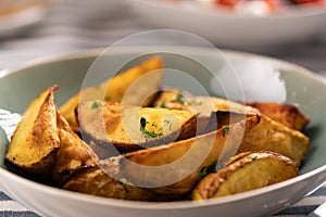 Roasted potatoes. Baked potato wedges in plate on table, close-up.