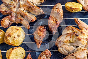 Roasted Potatoes and Chicken Slices on Stainless Steel Cooking Grid. Grilled Chicken Breast with Slices Made for Marinade to