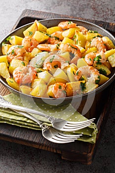 Roasted potatoes with garlic, herbs and shrimp close-up in a plate. Vertical