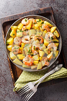 Roasted potatoes with garlic, herbs and shrimp close-up in a plate. Vertical top view