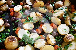 Roasted potatoes with olives and tomatoes, food background
