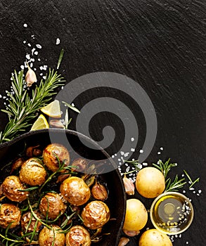 Roasted potatoes with rosemary, garlic, lemon and sea salt on a black background