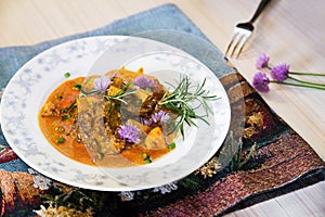 Roasted poultry liver,apple, curry sauce. On white plate with chive flower.