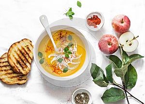 Roasted pumpkin and apples vegetarian soup on light background, top view. Flat lay. Healthy vegetarian food