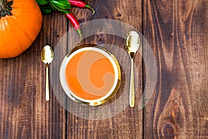 Roasted pumpkin and carrot soup with cream and pumpkin seeds on white wooden background. Copy space. Flat lay. Food porn