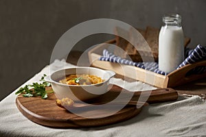 Roasted pumpkin and carrot soup with cream and toast on wooden background. Copy space