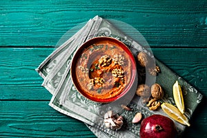 Roasted red bell pepper spread - muhammara - in a red bowl with various ingredients