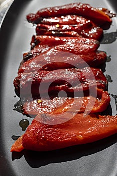 Roasted red bell peppers on a black platter as a side dish