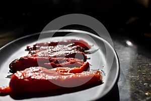 Roasted red bell peppers on a black platter as a side dish