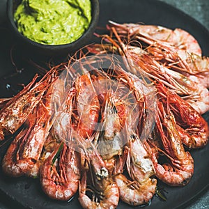 Roasted red shrimps with guacamole avocado sauce in black plate