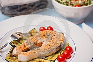 Roasted salmon and green zucchini with vvegetables salad in background