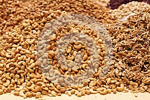 Roasted salted cashews, raw walnuts and almonds, lying on a large counter at the market in Deira, Dubai