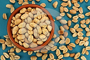 Roasted salted peanuts in bowl on blue background, top view