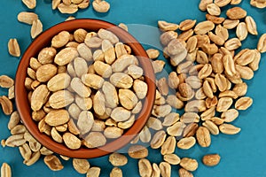 Roasted salted peanuts in bowl on blue background, top view