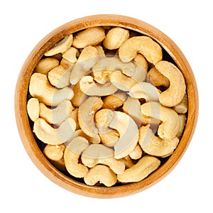 Roasted salted whole cashews in wooden bowl over white