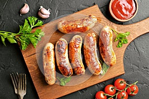 Roasted sausages on a cutting board, sause and cherry tomatoes