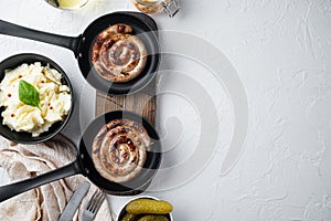 Roasted sausages with fermented cabbage in cast iron frying pan, on white background, top view flat lay , with space for text