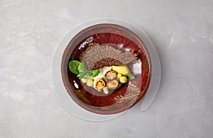 Roasted sea scallops with celery mash and zucchini balls on dark handmade ceramic dish. Seafood dish in modern serveware on gray