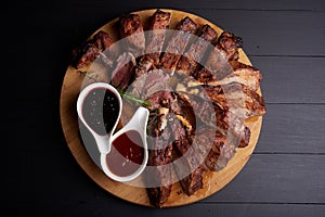 Roasted sliced barbecue pork ribs with aromatic herbs and two kinds of souce, top view