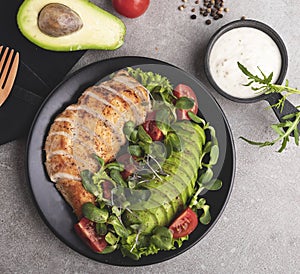 Roasted sliced chicken fillet with avocado, tomatoes and herbs on a plate healthy nutrition