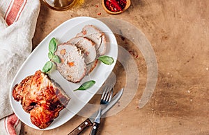 Roasted sliced pork ham on a white plate on a beige rustic background