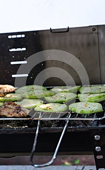 roasted sliced zucchini on a fire laid out in rows on the grill under burning coals. Meat in barbeque. Chicken steak with